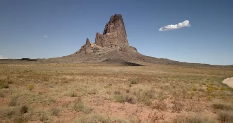 Flying low and fast then rising toward massive stone mountain in desert Stock Footage 117863656