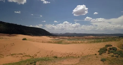 Flying low and slow over grassy sand dunes under perfectly puffy clouds Stock Footage 119121750