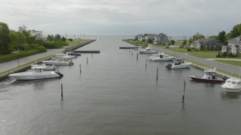 Flying low over a boat-lined canal as it leads into Great South Bay in LI Stock Footage 242497451