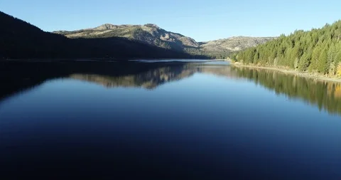 Flying low over a calm reflective mountain lake Stock Footage 98310958