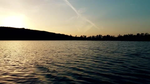 Flying low over lake in an evening day with mountain siluetes in the background Video stock 154385322