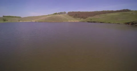 Flying low over the lake, taking off over the hill, horizon of a plowed field Stock Footage 66879452
