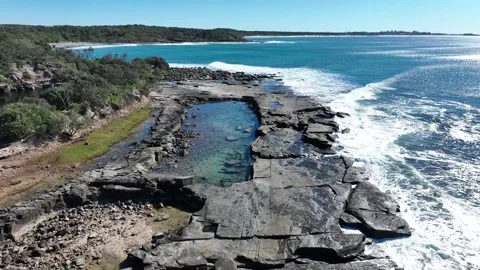 Flying low over a rocky beach, the camera looks down into clear rock pool Stock-Footage 331016872