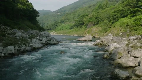 Flying low over small rapids in river through canyon on sunny day Stock Footage 214930662