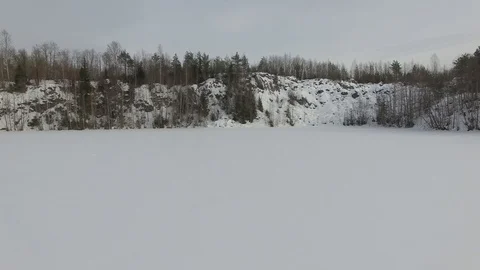 Flying low over snow-covered frozen lake towards rocky hill Stock Footage 92855836