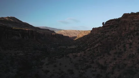 Flying low through a wide desert canyon in sunset shadows Stock Footage 133757442
