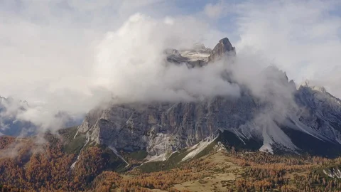 Flying in the middle of clouds, the Pelmo mountain and a forest , Dolomites Stock Footage 129813157