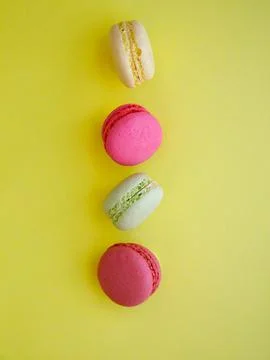 Flying multi-colored assorted bright macarons close-up on yellow background Foto stock