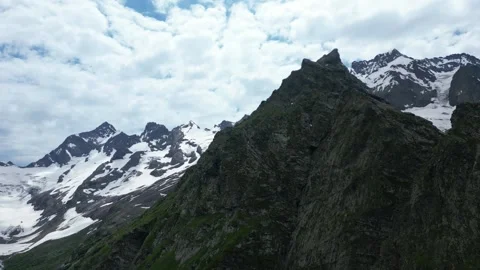 Flying next to a cliff view of snowy cliffs from behind Stock Footage 307878467