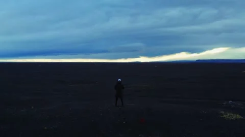 Flying out from back of man in black jacket on volcanic field, Iceland 動画素材 168077121