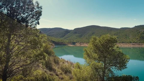 Flying out between green trees towards blue turquoise mountain lake. Aerial view Stock Footage 86281210