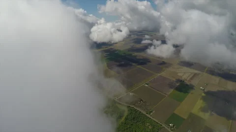 Flying out of clouds toward farm lands and river Vídeo Stock 240416677