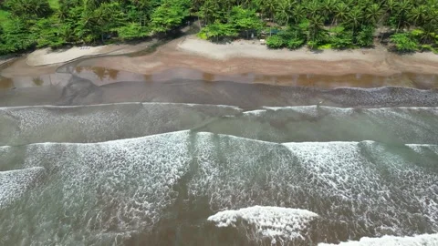 Flying over 7 ondas beach with the waves breaking and the dark colored sand Stock Footage 328693614