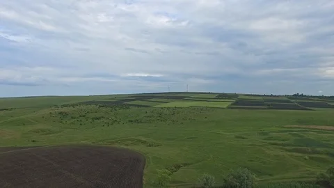 Flying over agricultural fields with wind turbine on background Stock Footage 99334942