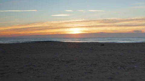 Flying over the beach and ocean water during a sunrise Vidéo 100410883