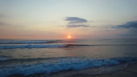 Flying over beautiful ocean waves and surfers at sunset. Aerial footage. Stock Footage 81214810