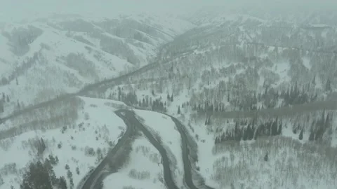 Flying over a bend in the road on a mountain pass, a winter cloudy day with snow Stock Footage 236400383
