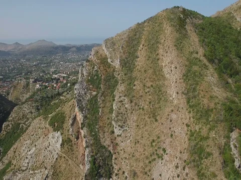 Flying over big rocky mountain ridge towards valley with old european village. Stock Footage 78007299