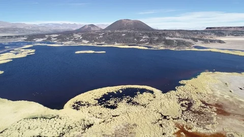 Flying over blue and red lagoon showing black Alumbrera and Antofagasta volcanos 스톡 동영상 103483579