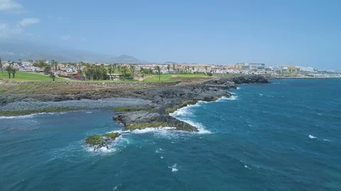 Flying over blue ocean towards golf course green fields in sunny day Video stock 90555756