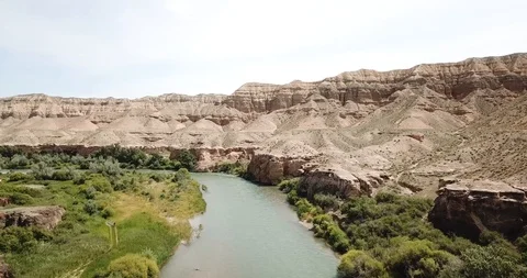Flying over the blue river. Wide river. On the shore of green grass, hills. Video stock 100767447