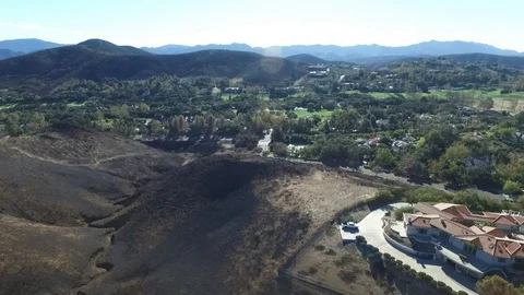 Flying over a burned up hillside towards a lush golf course Stock Footage 100339292