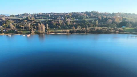 Flying over a  calm lake and then over a green hill, 4k Stock Footage