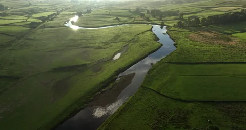 Flying over a calm river in the green valley at sunrise Video stock 248924401