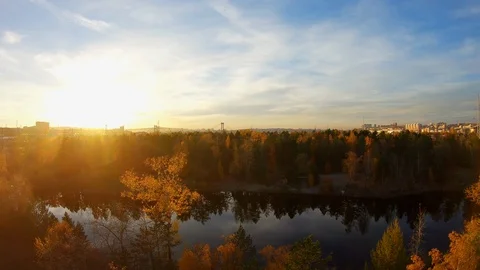 Flying over a city pond surrounded by yellowed autumn trees at sunset Stock Footage 124398883