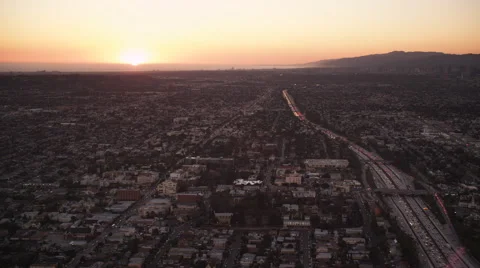 Flying over cityscape and freeways of Los Angeles with sunset in distance. Shot Stock Footage 59526088