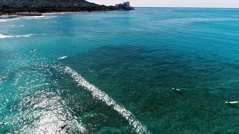 Flying over clear blue water with surfers towards Kaimana beach and Video stock 109367367