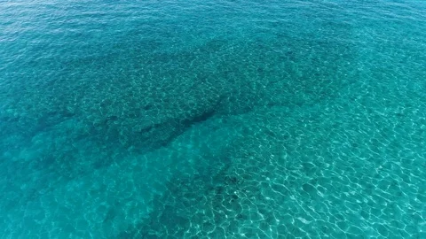 Flying over clear blue water with minimal waves flowing over the surface. Video stock 109455065