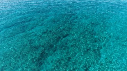 Flying over clear blue water, slowly tilting up revealing the horizon. Video stock 109455092