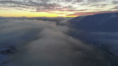Flying over the clouds among the snow-capped mountains at sunset. Aerial view 스톡 동영상 152589033