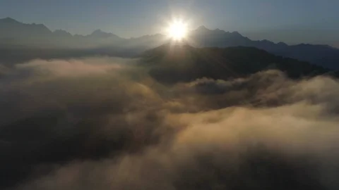 Flying over the clouds or mist in mountains in backlight on sunrise. drone shot Stock Footage