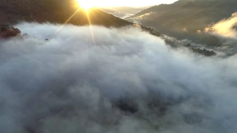 Flying over the clouds at sunset. Aerial view of beautiful foggy mountains. UHD Stock Footage 119471462