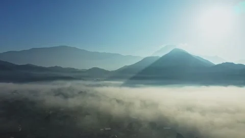 Flying over clouds towards mountains on a sunrise Vídeos de archivo 265604567