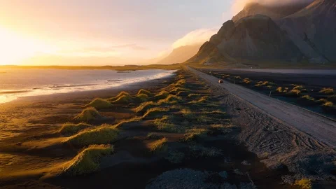 Flying over a dirt road at sunset with Vestrahorn mountain in Iceland Stock Footage 125367146
