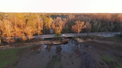 Flying over dry pond with passing car over broken a dam, forest in the distance. 스톡 동영상 90157600