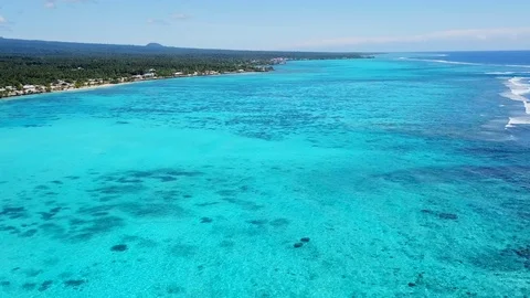 Flying over edge of tropical reef looking down at blue lagoon 動画素材 107089893