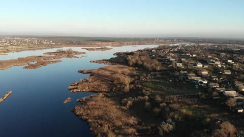 Flying over the estuary of a river and village. There are dry reeds on the bank Stock Footage 158690987