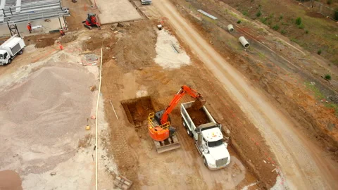 Flying over an excavator dumping dirt into a dump truck at construction site Stock Footage 135205891