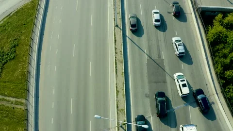 Flying over a fast-moving stream of cars at the roundabout of large metropolis. Video stock 134970887