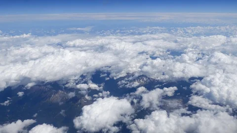Flying over fluffy white clouds with a partial view of the rural landscape Stock Footage 92981968