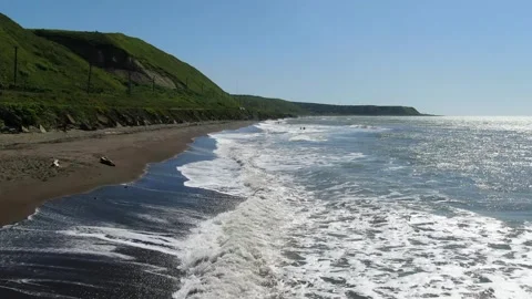 Flying over the foamy waves of the Sea of Okhotsk, running onto a sandy beach Stock Footage 232879314