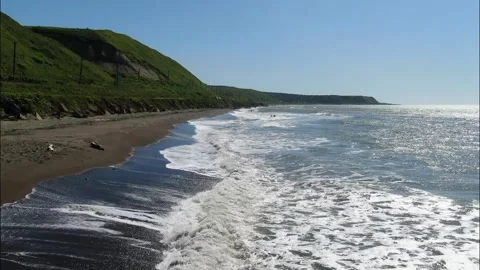 Flying over the foamy waves of the Sea of Okhotsk, running onto a sandy beach Stock Footage 232994055
