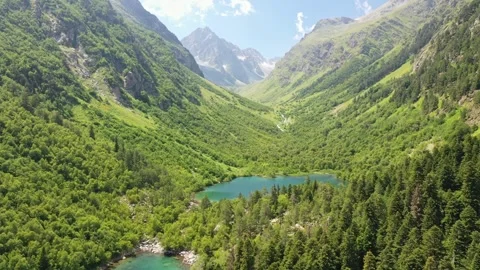 Flying over a forest and two lakes with turquoise water among the mountains in Stockbeeldmateriaal 263251240