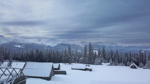 Flying over the forest, mountains and shepherd houses in winter Stock Footage 104847837