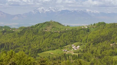 Flying over forest ridge with waving flag, church and Alps in background Stock Footage 274300804