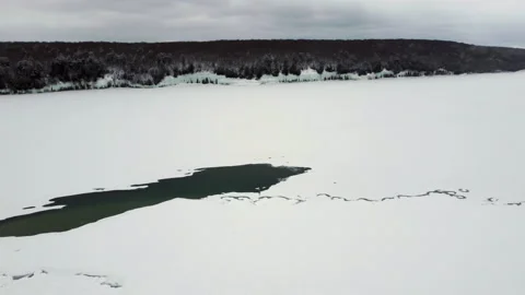 Flying over a frozen lake on a cloudy day. The Great Lake is covered with ice Stock Footage 205873974